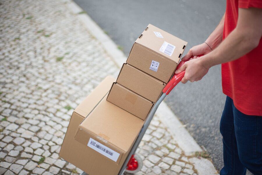 Repartidor con carrito de cajas en una calle empedrada
